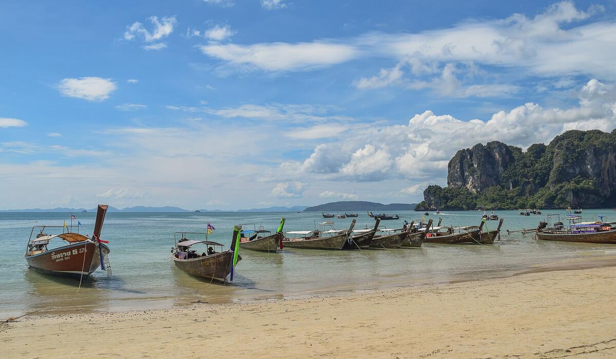 Longtail boats on Railay beach under limestone cliffs